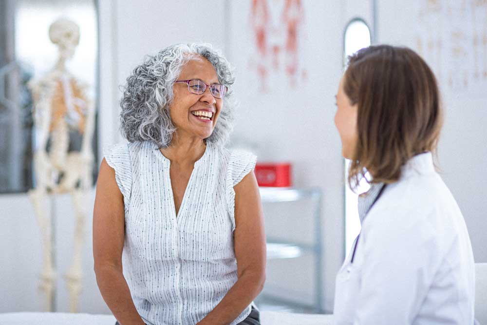 Photo of woman smiling and talking to her primary care provider in a Care4U Center setting